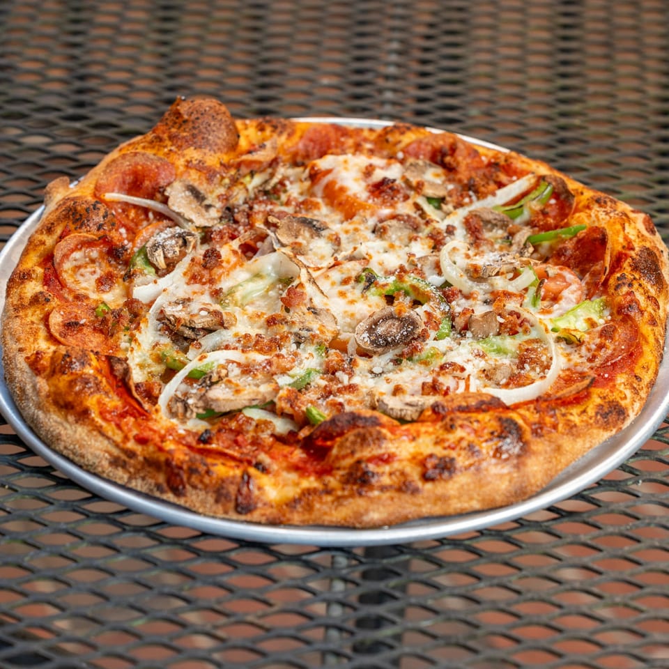 Homegrown Pizza's pepperoni, mushroom, onion, and green pepper pizza on a metal table.
