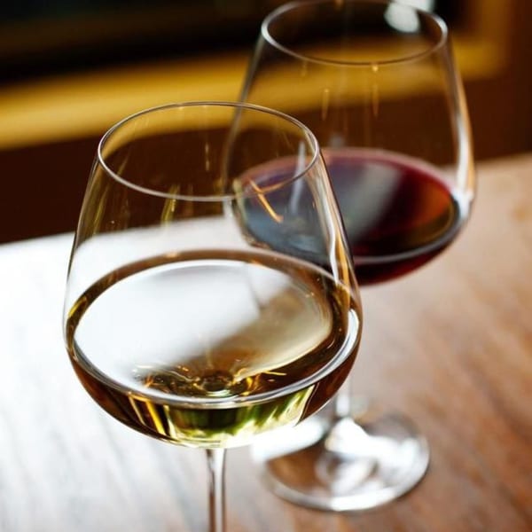 Two wine glasses, one with white wine and one with red wine, on a wooden table.