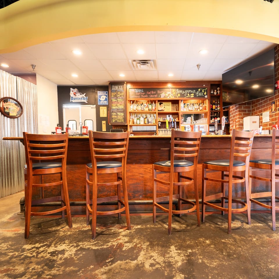 The Homegrown Pizza bar with wooden stools, a chalkboard menu, and bottles of liquor.