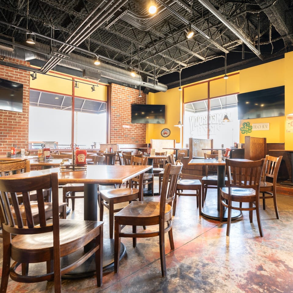 Interior of Homegrown Pizza with wooden tables and chairs, brick walls, and large windows.